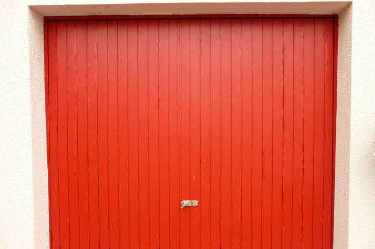 Porte de garage rouge fermée, composée de panneaux verticaux